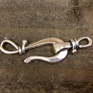 May include: Silver-toned metal clasp with a loop on one end and a hook on the other. The clasp is designed to be used for jewelry making.