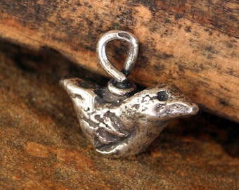 May include: A silver bird charm with a textured surface and a loop for attaching to a necklace or bracelet.