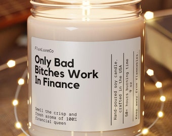 May include: A lit soy candle in a clear glass jar with the text "Only Bad Bitches Work In Finance." The candle sits on a round wooden coaster. The candle is hand-poured in the USA and has a 50+ hour burn time.