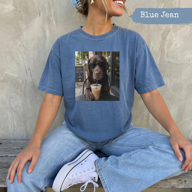 Dog wearing sunglasses in a coffee shop, printed on a blue t-shirt.