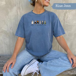 Blue crewneck t-shirt with "Just a Spooky Cow" text and Halloween costume cows graphic.