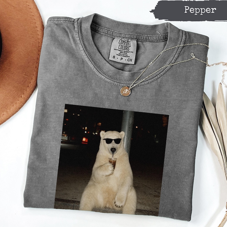 Gray t-shirt with a graphic of a polar bear wearing sunglasses holding a drink.