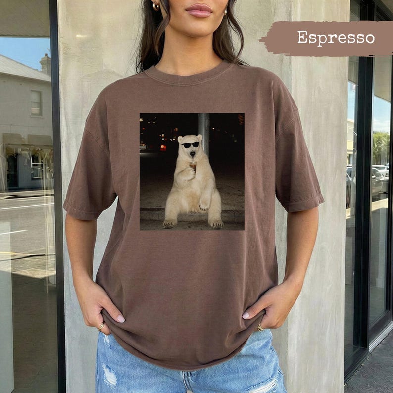 Brown t-shirt with graphic of a polar bear wearing sunglasses holding a drink.
