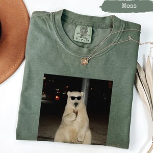 Green t-shirt with graphic of polar bear wearing sunglasses.