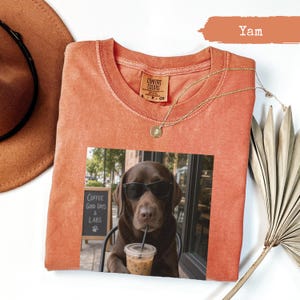 Orange crewneck t-shirt featuring a chocolate lab wearing sunglasses holding a coffee cup.