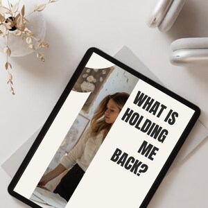 Puede incluir: Una tableta mostrando un fondo blanco con texto negro que dice "What is holding me back?" Una mujer con una camisa blanca y pantalones negros es parcialmente visible en el fondo.