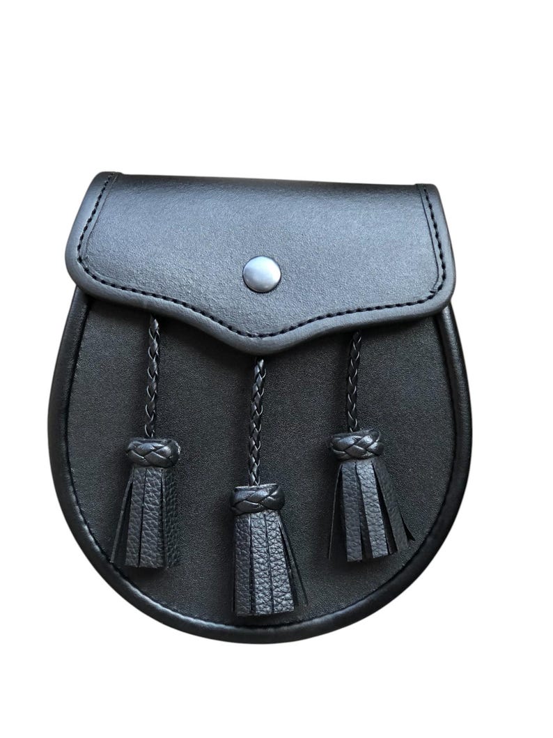 May include: A black leather sporran with three tassels. The sporran has a flap with a button closure.