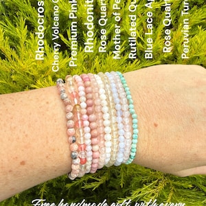 May include: A collection of nine beaded bracelets featuring various gemstones including Rhodocrosite, Cherry Volcano Quartz, Premium Pink Opal, Rhodonite, Rose Quartz, Mother of Pearl, Rutilated Quartz, Blue Lace Agate, and Peruvian Turquoise.