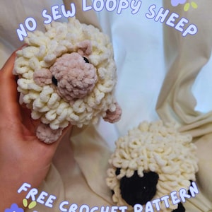 May include: Two handmade crochet sheep toys. One is held in a hand, the other is on a cream-colored surface. The sheep have fluffy, cream-colored bodies, pink faces and feet, and black eyes. Text on the image reads "NO SEW LOOPY SHEEP" and "FREE CROCHET PATTERN".