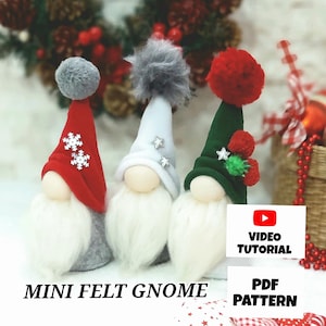 Puede incluir: Tres adornos de gnomo de fieltro con sombreros de diferentes colores. Los gnomos llevan sombreros rojos, verdes y blancos con pompones. Los gnomos tienen barbas blancas y están sentados sobre una superficie blanca. La imagen incluye el texto "MINI FELT GNOME", "VIDEO TUTORIAL" y "PDF PATTERN".
