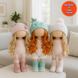 May include: Three handmade dolls with long blonde and red hair, wearing pink and white outfits. The dolls have different hats: a pink cat-ear hat, a blue turban, and a white knit hat. The image includes text that says "Pdf Pattern & Video Tutorial".