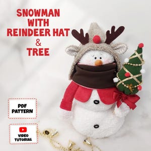 May include: A plush snowman wearing a reindeer hat and a red scarf, holding a small green Christmas tree. The snowman has a brown scarf and a carrot nose. The image includes the text "Snowman with Reindeer Hat & Tree".