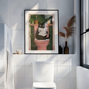 Puede incluir: Un gato negro sentado en un inodoro rosa leyendo un periódico en un baño con azulejos blancos y una impresión enmarcada de la misma escena.