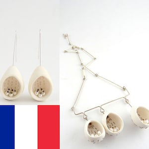 May include: A set of white ceramic earrings and a necklace with three pendant charms. Each piece features a small, open-topped basket filled with white pearls.