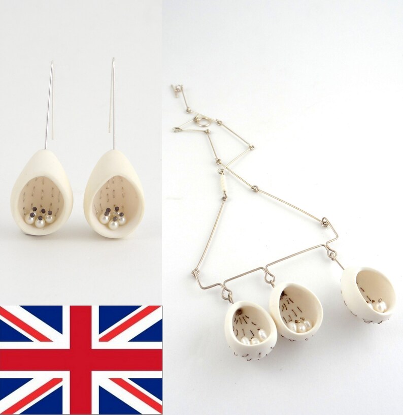 May include: A set of white ceramic earrings and a necklace with three pendant charms. Each piece features a small, open-mouthed cup shape with a textured surface and a few white pearls inside.