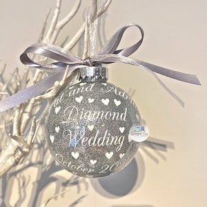 Puede incluir: Adorno de Navidad de purpurina plateada con texto blanco que dice "[Name] y [Name] Diamond Wedding Octubre 20[Year]" con corazones blancos que rodean el texto.