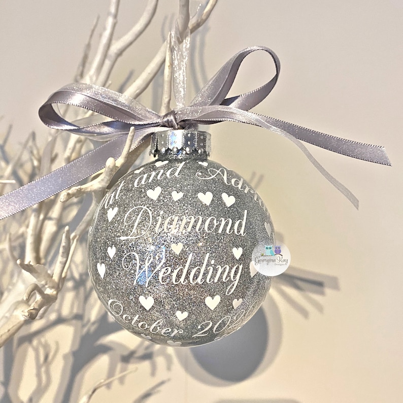 Puede incluir: Adorno de Navidad de purpurina plateada con texto blanco que dice "[Name] y [Name] Diamond Wedding Octubre 20[Year]" con corazones blancos que rodean el texto.