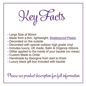 May include: Key Facts about a large, 80mm shatterproof plastic bauble. It is decorated with special outdoor vinyl, UK made satin and organza ribbons, and glitter applied to the inside. The bauble is custom made to order and comes in a luxury black gift box.  Please see product description for full information.