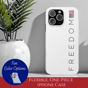 May include: White iPhone case with the word "FREEDOM" printed vertically and an American flag graphic. The case is shown with a triple-lens camera and a white background. The case is described as flexible and one-piece.