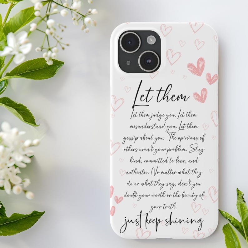 Pu&ograve; includere: Una custodia per iPhone bianca con un design rosa e bianco. La custodia presenta una citazione che recita: "Lascia che ti giudichino. Lascia che ti fraintendano. Lascia che parlino di te. Le opinioni degli altri non sono il tuo problema. Rimani gentile, impegnato nell'amore e autentico. Non importa cosa facciano o dicano, non dubitare mai del tuo valore o della bellezza della tua verit&agrave;. Continua a brillare."