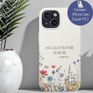 May include: White iPhone case with a floral design featuring red, blue, and purple flowers. The case has the text "I HAVE CALLED YOU BY NAME, YOU ARE MINE. -Isaiah 43:1" and a blue circle with "Christian iPhone Case Isaiah 43:1".