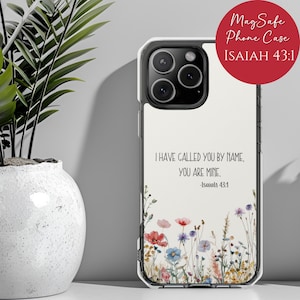 May include: Clear phone case with a floral design and the text "I HAVE CALLED YOU BY NAME, YOU ARE MINE. -Isaiah 43:1". The case also has the text "MagSafe Phone Case ISAIAH 43:1" in a red circle.