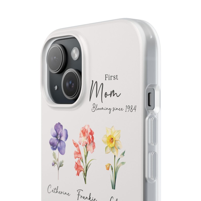 May include: White phone case with a floral design and the text "First Mom Blooming since 1984".
