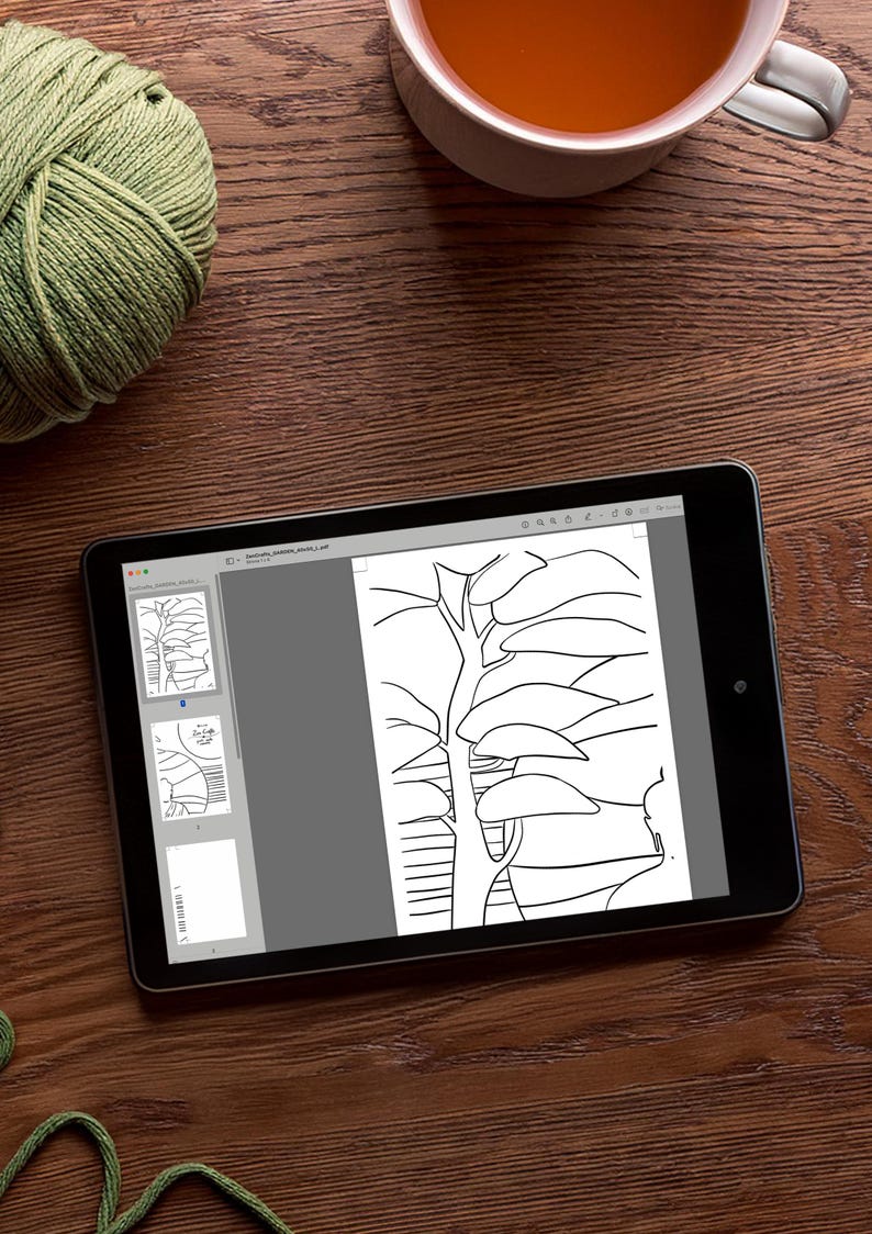 May include: A digital tablet displaying a black and white line drawing of a tree with branches and leaves. The tablet is on a wooden surface.