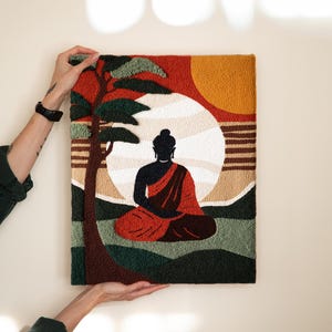 May include: A colorful needlepoint wall hanging featuring a silhouette of Buddha meditating under a large sun with a palm tree in the background.