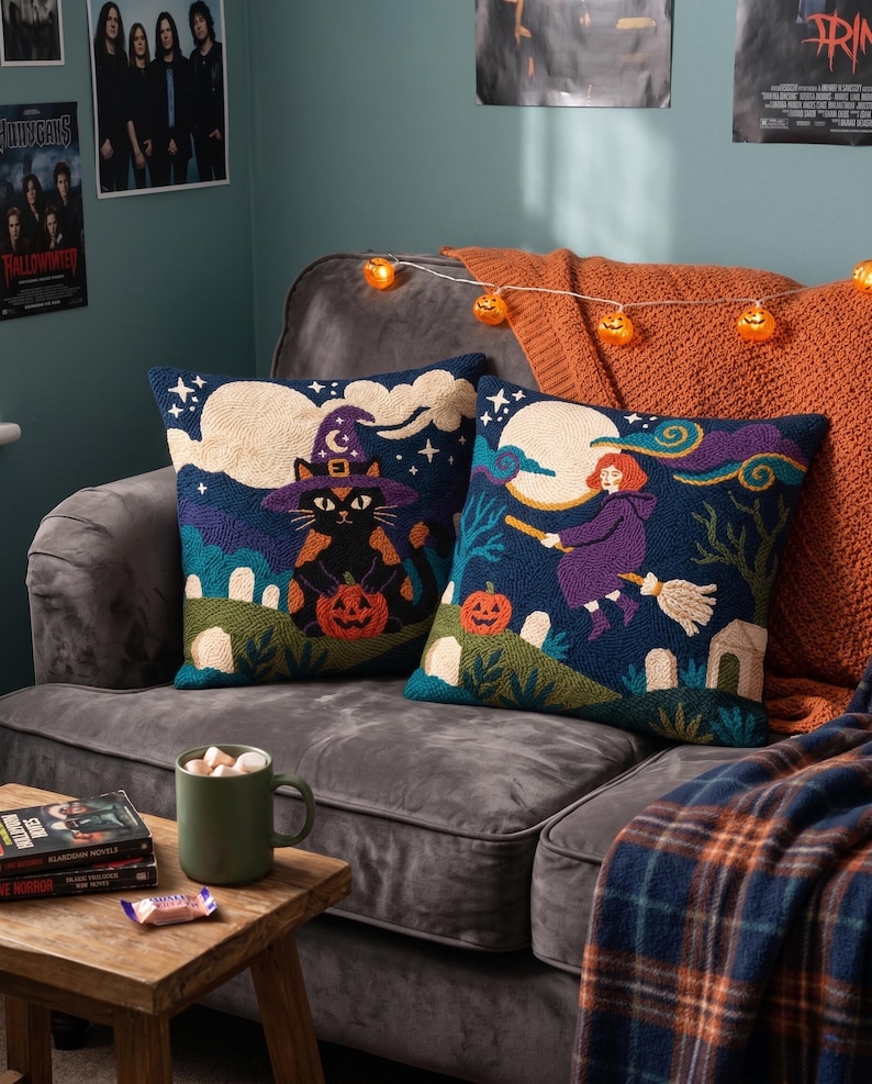 May include: Two square throw pillows featuring punch needle embroidery with Halloween themes. One pillow displays a black cat wearing a purple witch hat holding a pumpkin. The other pillow shows a person flying on a broomstick past a full moon.