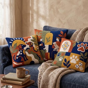 May include: Three square throw pillows featuring textured punch needle embroidery in a vibrant palette of navy blue, mustard yellow, burnt orange, and cream. The designs depict stylized dogs, people, paw prints, and tennis balls in a grid pattern.
