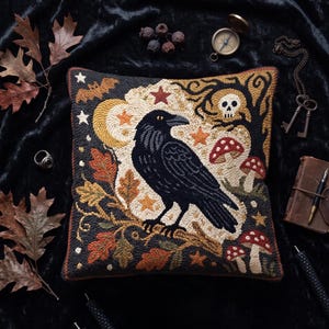 May include: A square throw pillow featuring a detailed needlepoint design of a black raven perched on an oak branch. The scene includes a yellow crescent moon, red and white mushrooms, a skull in a tree, stars, and a bat against a dark background.