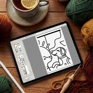 May include: A tablet displaying a digital coloring page of a dog, surrounded by several balls of yarn in various colors, a wooden crochet hook, a white stylus, and a ceramic mug containing tea with a lemon slice on a wooden surface.