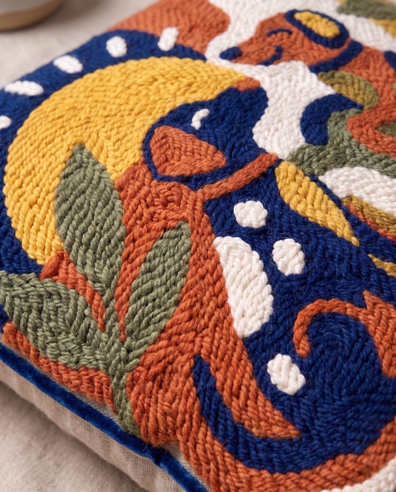 May include: A square throw pillow featuring a textured punch needle design with a vibrant pattern of abstract shapes in shades of deep blue, mustard yellow, terracotta orange, sage green, and white, finished with a dark blue velvet piping edge.
