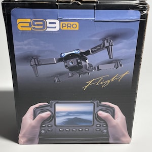 Puede incluir: Caja negra con un dron y el texto "E99 PRO" y "Flight". La imagen muestra un dron con una cámara y un mando a distancia con pantalla. La caja también tiene las palabras "Intelligent Quadcopter Flying Drone".