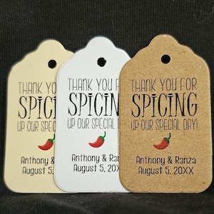 May include: Three wedding favor tags with a red chili pepper graphic and the text "Thank you for spicing up our special day!" The tags are on different colored backgrounds: beige, white, and brown.