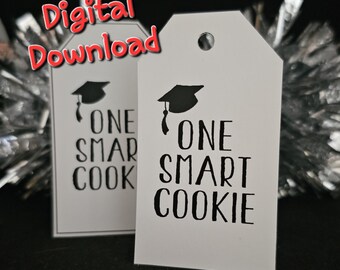 May include: Two white gift tags with black text and a black graduation cap graphic. The text on the tags reads "One Smart Cookie".