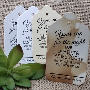 May include: Four white and cream-colored gift tags with a scalloped edge and a hole punched at the top. The tags have black text that reads "Your cup for the night for whatever tastes right!" and "Write your name here".