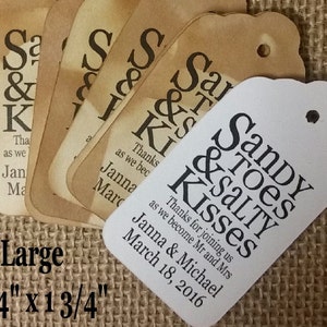 May include: A set of six white favor tags with black text that reads "Sandy Toes & Salty Kisses" with the text "Thanks for joining us as we become Mr. and Mrs. Janna & Michael March 18, 2016". The tags are 3 1/4 inches by 1 3/4 inches.