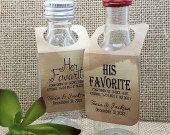 May include: Two small glass bottles with brown paper labels. The labels have the text "Her Favorite" and "His Favorite" with the text "Your drink of choice here (maybe two lines if needed)" and the names "Tonia & Jackson" and the date "December 31, 2022".