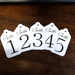 May include: Five white gift tags with black text. Each tag has the word "Bottle" and a number from 1 to 5.
