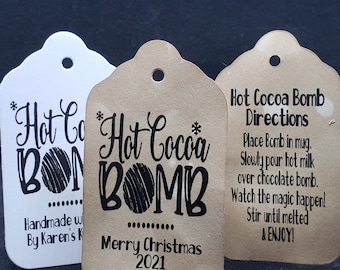 May include: Two brown paper gift tags with black text and a black and white illustration of a hot cocoa bomb. The text on the tags reads "Hot Cocoa Bomb" and "Merry Christmas 2021". The third tag is white with black text that reads "Hot Cocoa Bomb" and "Handmade with love by Karen's Kitchen".