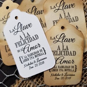 May include: White gift tags with black text that reads "La Llave a la Felicidad es el Amor" and "Y la habilidad de abrir una botella". The tags also include the names "Nicholas & Lucianna" and the date "Jan 20 2018".