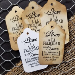 May include: Five rustic brown and white paper gift tags with the text "La Llave a la Felicidad es el Amor" and "Y la habilidad de abrir una botella" with the names Nicholas & Lucianna and the date Jan 20 2018.