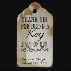 May include: A rustic brown wedding favor tag with the text "Thank you for being a Key Part of Our Past, Present, and Future." The tag also includes the names "Jessica & Douglas" and the date "March 10th, 2017".