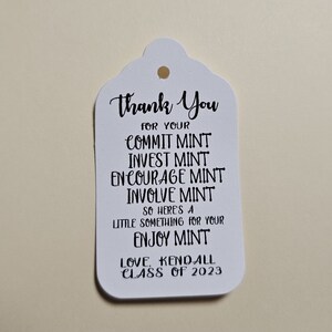 May include: White gift tag with black text that reads "Thank You for your Commit Mint, Invest Mint, Encourage Mint, Involve Mint, So here's a little something for your Enjoy Mint. Love, Kendall Class of 2023".