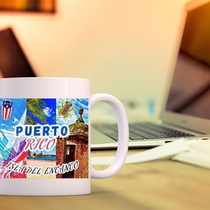 May include: White ceramic mug with a colorful design featuring a Puerto Rican flag, a frog, a building, and the text "PUERTO RICO ISLA DEL ENCANTO".