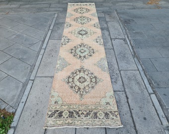 May include: A long, rectangular rug with a peach background and a traditional Persian design. The rug has a dark brown border with a light brown and green pattern.
