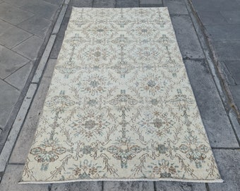 May include: A vintage cream-colored rug with a repeating pattern of brown and blue floral designs.