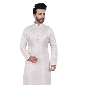 Op de afbeelding: Een witte, langarmige kurta met een geometrisch patroon. De kurta heeft een mandarijnkraag en een knoopsluiting. Het model draagt een witte broek en bruine schoenen.